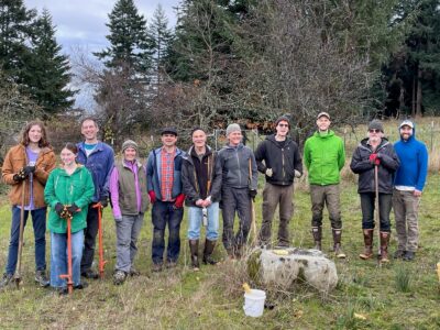 Group of smiling, colorfully dressed people on grass after planting native trees